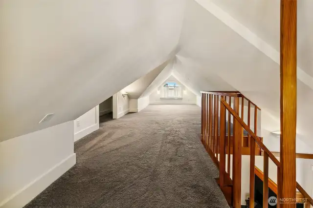 Perched above the living room, Apartment 7’s loft stretches over 30 feet and offers a rare sense of volume and versatility—ideal as a sleeping area, creative studio, or cozy retreat. Pitched ceilings and a large gable-end window add charm, while a solid timber railing and carpeted floors bring comfort and safety. A unique space that transforms this apartment into a true urban hideaway.