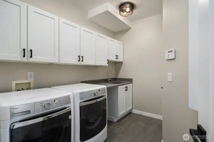 A well-designed laundry room with Maytag appliances, quartz counter+deep utility sink keeps life organized.