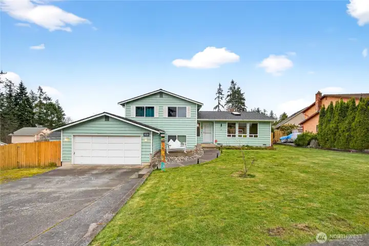 Attractive split-level home with a two-car garage and expansive front yard, offering inviting curb appeal and a welcoming residential setting.