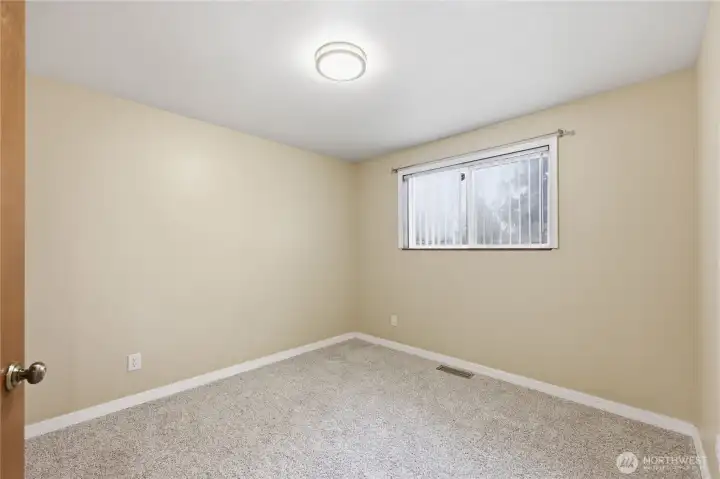 Light-filled additional bedroom with a window overlooking the backyard, ideal for guests or a home office.