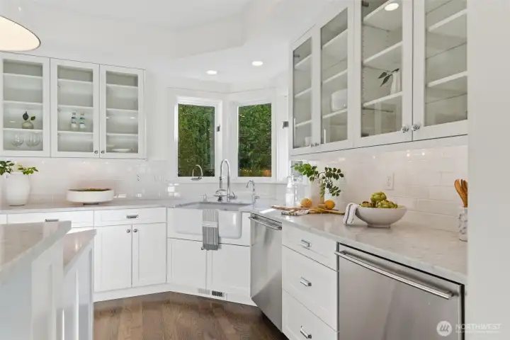 Authentic Carrara Marble countertops and a pair of Bosch dishwashers makes clean up and entertaining a breeze. Upper cabinets with glass fronts add softness and reflection, perfect for displaying both beautiful serve ware and everyday dishes. The Rohl Shaws apron-front sink, handmade in England, perfectly punctuates the space. There is also a dedicated filtered water faucet here, with replaceable Everpure filter under the sink.