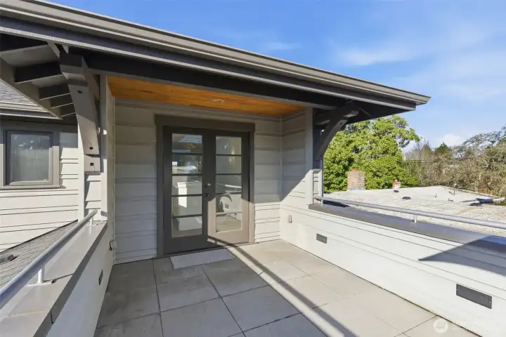 French doors and cedar soffit with partially covered area leading back to the upper level.