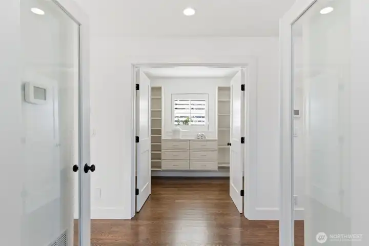 Double French doors lead to the primary suite, as well as the walk in closet. There is a separate thermostat here for the upper zone heating/cooling system. The keypad to the right is for the Bosch wired security system. The home also benefits from a central vacuum, including a brand new (still in box) accessories kit.