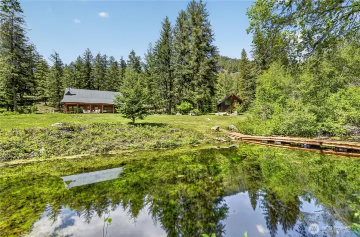 Seasonal spring fed pond and walking bridge are at the base of the lawn, home and garage.