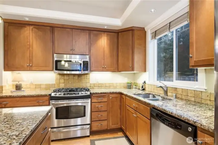 Spacious kitchen with stainless steel appliances, travertine backsplash, granite countertops, and a large island designed for gathering, highlighted by a coffered ceiling. Spacious kitchen with stainless steel appliances, travertine backsplash, granite countertops, and a large island designed for gathering, highlighted by a coffered ceiling.