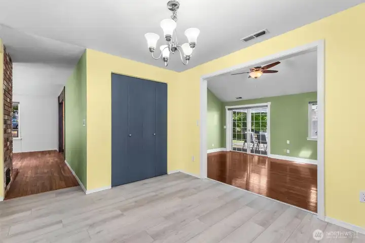 Hallway to the left to the living room and stairs. Family room to the right with tall vaulted ceilings, hardwood floors, and slider to the patio.