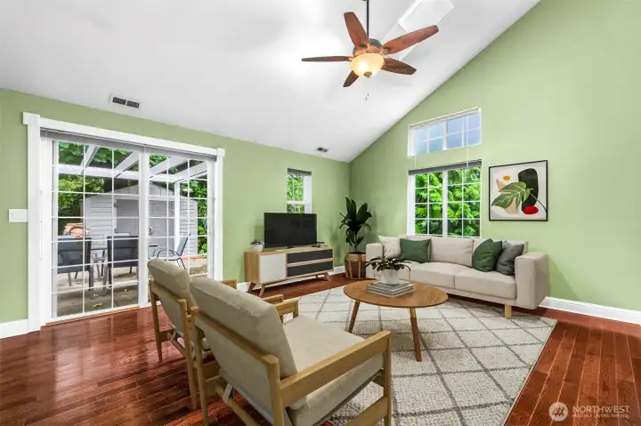 The light and bright family room features lots of space, high vaulted ceilings and a slider to the patio area. This photo is virtually staged.