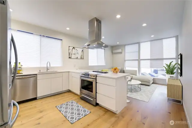 Quartz counters and breakfast bar in spacious kitchen w/stainless steel appliances.