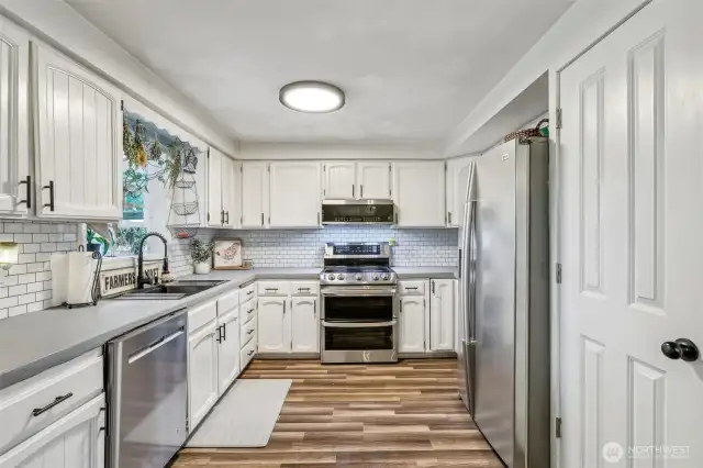 Kitchen showcasing white, farm style cabinetry & stainless-steel appliances