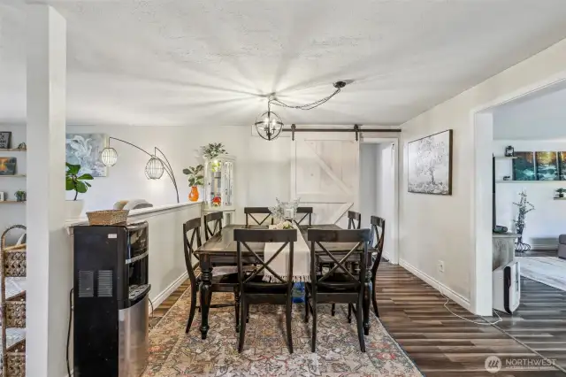Dining area with sliding barn-style door leading into master bed & bath
