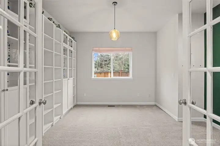 French doors open up to a beautiful main floor office with built-in shelving