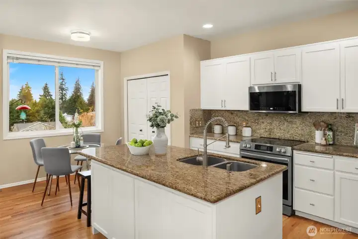 Modern kitchen with an open layout, pantry storage, new stainless appliances and slab granite countertops.