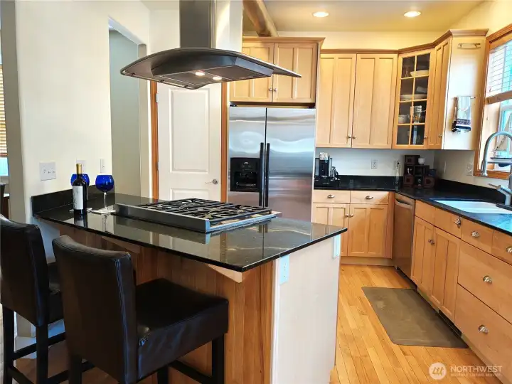 Breakfast bar overlooks stainless steel gas stove with custom stainless hood. Your guests can keep you company while you are preparing a feast.