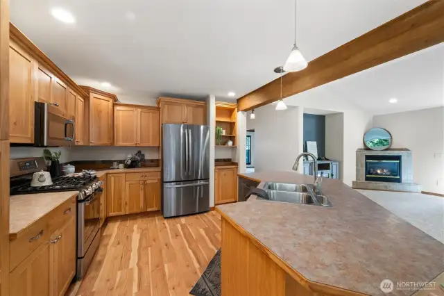 The kitchen features stainless steel appliances, rich wood cabinetry, and a breakfast bar for casual dining