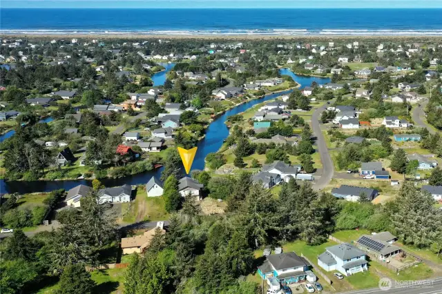 View of 137 N Razor Clam Dr SW on the Bell Canal, with the Pacific Ocean and beach in the background.
