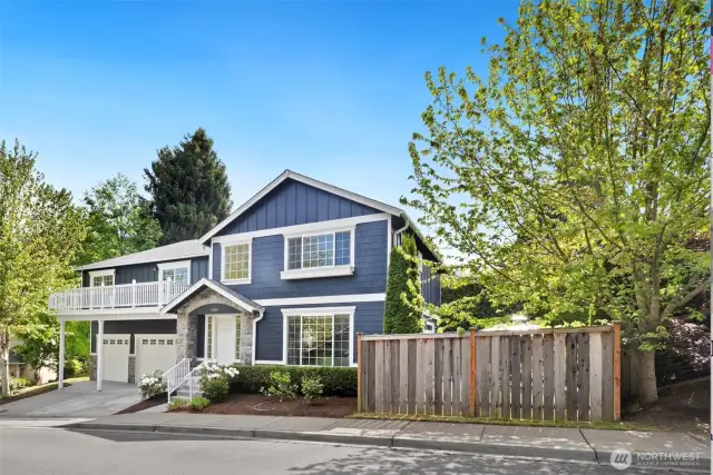 Corner-lot curb appeal shines at this beautifully maintained home, with a navy exterior, stone accents, and crisp white trim that feels timeless and fresh.