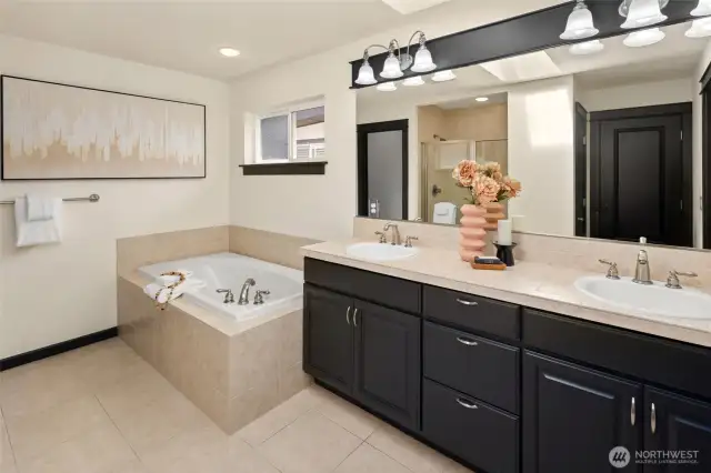The large primary bathroom features dual vanities, updated lighting, and a soaking tub ready for relaxing evenings.