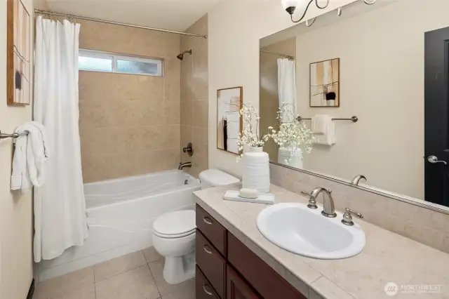 The main upstairs bath offers a clean, classic design with generous counter space and full-size tub for daily routines or weekend wind-downs.