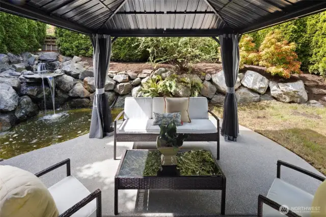 Surrounded by lush landscaping and stonework, this tranquil water feature brings natural beauty and a calming ambiance to the backyard.