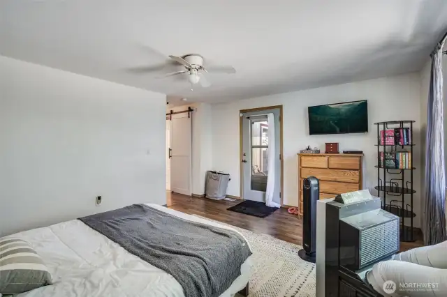 Primary suite includes full bathroom through the barn door, direct backyard patio access through man door, and a huge walk in closet