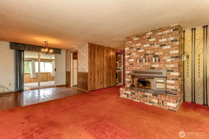 Living room with custom brick fireplace & wood stove insert, looking into sun room
