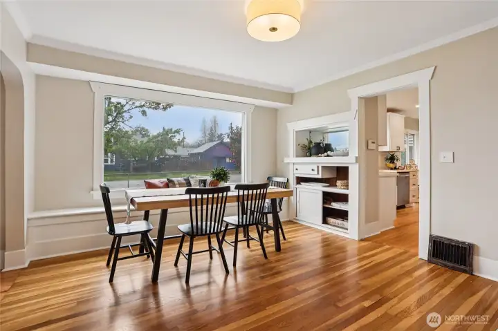 Bright dining space with warm hardwoods and oversized windows, perfect for everyday meals or hosting. Charming built-ins add character and function, while the bench seating offers hidden storage—thoughtful, practical, and effortlessly inviting.