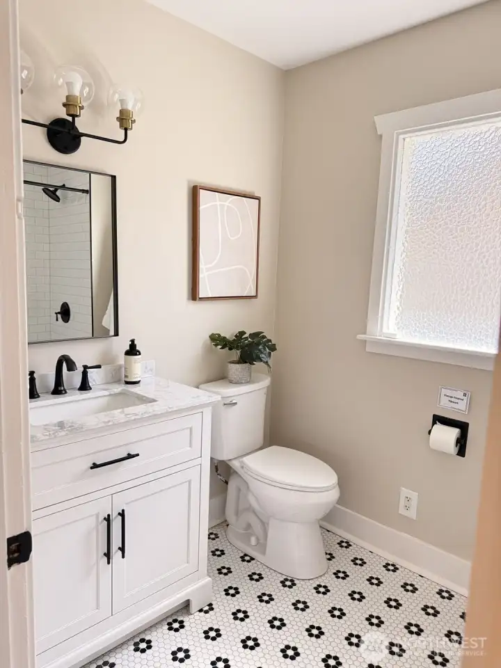 Stylishly updated bath with timeless finishes—quartz countertops, classic tile, and matte black fixtures create a clean, modern feel. Bright, fresh, and thoughtfully designed, it’s a space that feels both elevated and effortlessly livable.