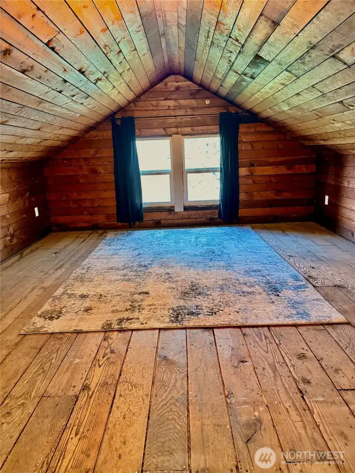 Cozy upper-level retreat with warm wood-lined ceilings and original plank floors—full of character and charm. Shown here virtually staged as a bedroom, this inviting space offers a peaceful escape and endless potential.