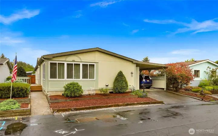 Parkway Village #77 Welcomes You! Covered carport parking, landscaped low-maintenance grounds and a south side front deck at the front entry