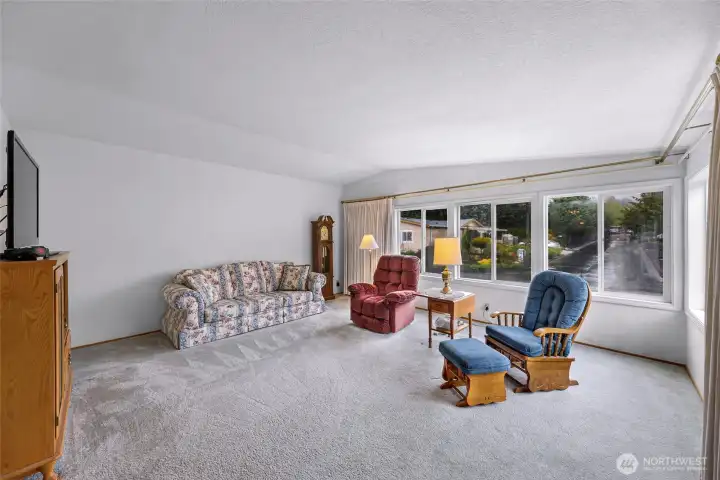 Large living room with oversized front-facing windows, abundant natural light, and spacious seating area