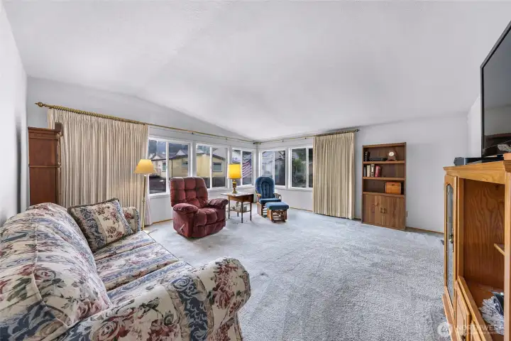 Large living room with wraparound windows, abundant natural light, and generous seating space