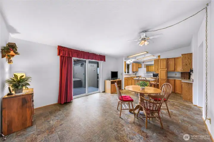 Open dining space with sliding glass door to deck, durable flooring, and adjoining kitchen layout ideal for entertaining