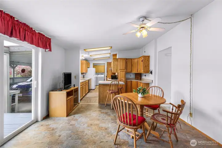 Dining area adjacent to kitchen with breakfast bar, abundant cabinetry, ceiling fan, and deck access through sliding glass doors