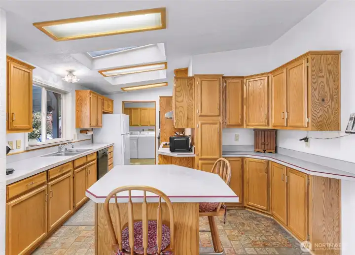 The kitchen with center island, skylights, extensive cabinet storage, and adjoining laundry area