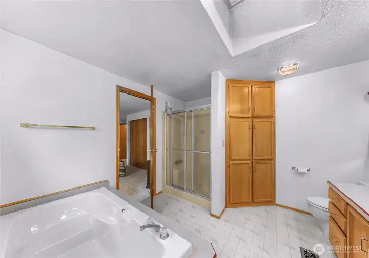 A relaxing soaking tub, separate shower, and abundant built-in storage cabinetry. Skylight provides natural light, while the open layout creates a bright and functional ensuite retreat