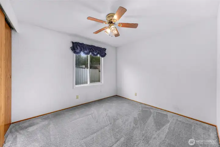Cozy guest bedroom #1 with natural light, ceiling fan, and versatile space for family, guests, or office use