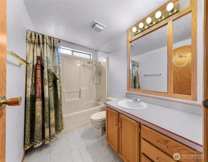 Full bathroom with large vanity, tub/shower combo, and additional storage cabinetry