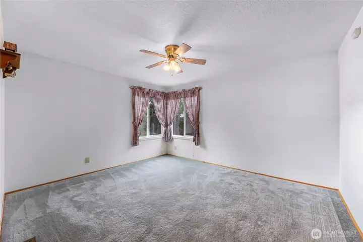 Comfortable 2nd bedroom with carpeting, ceiling fan, & corner windows