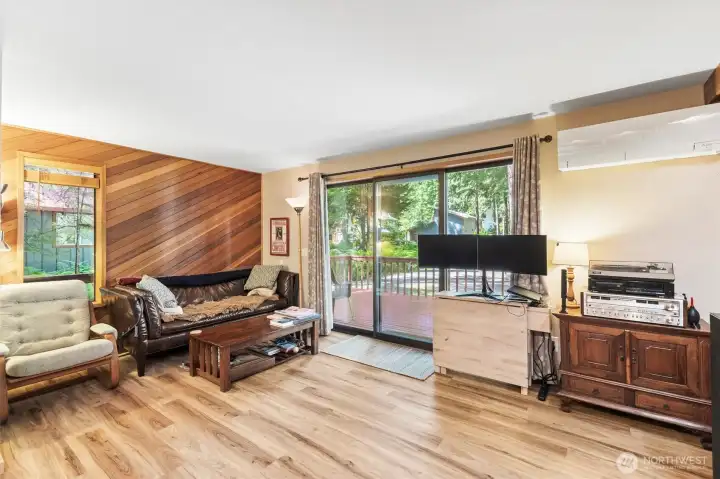 Bright living room with large windows that bring the surrounding forest indoors.