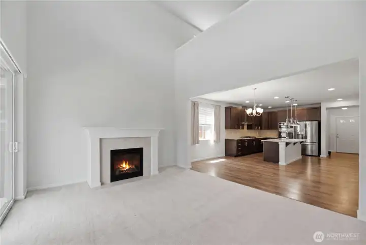 Living room with cozy fireplace, open to kitchen