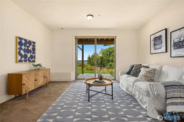 Downstairs flex space with sliding door out to a fenced yard facing the water.