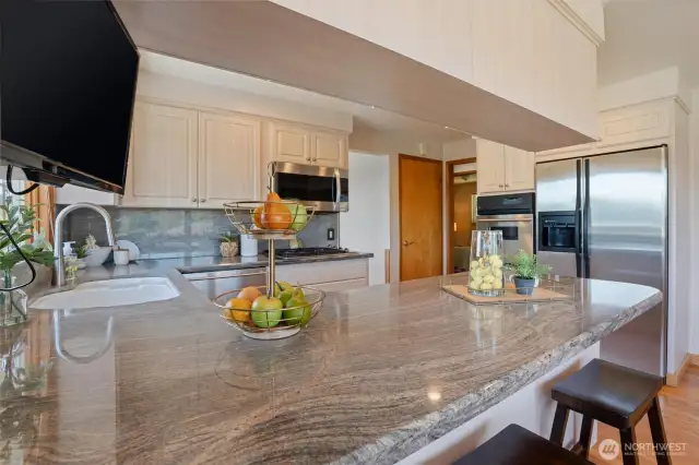 A no-edge sink allows for easy clean up. Beautiful granite countertops and stainless steel appliances add to the beauty of this kitchen.