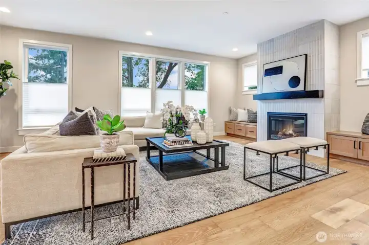 Inviting great room centered around a sleek, modern gas fireplace with custom tile surround, built-ins, and expansive windows framing natural light.