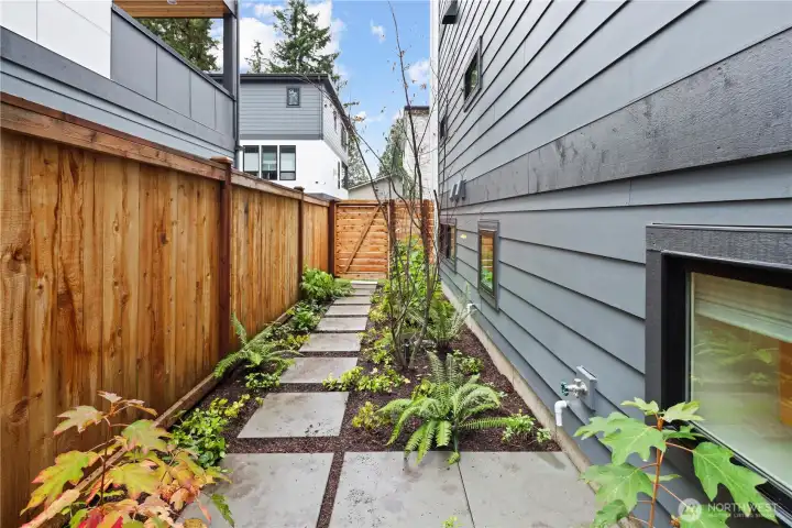 A thoughtfully designed side yard with planted beds, modern pavers, and landscape lighting. Flexible possibilities for a dog run or container garden.
