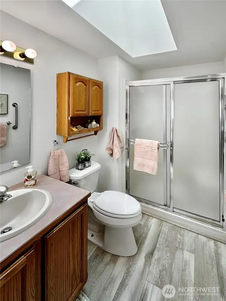 Primary 3/4 bath with laminate floor and skylight.