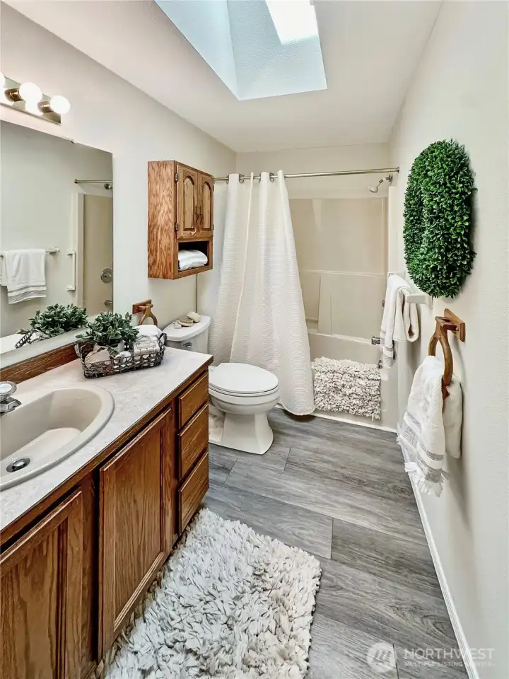 Hall bath close to both guest bedrooms...features laminate flooring, skylight for natural light and linen closet.