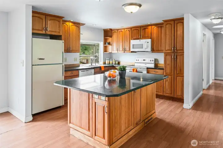 A kitchen that already has the footprint buyers are paying a premium for — oversized island, granite counters, crowned cabinets with raised panels in good shape, and sight lines straight through to the living area. Lots of space to pull up a bar stool and keep the cook company!