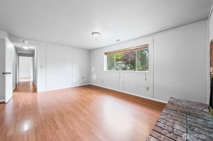 The second angle on the lower family room tells the full story — oversized footprint, easy-care laminate flooring, a picture window for tons of natural light overlooks the front yard. Direct hallway access connecting the whole lower level. This space adds serious livable square footage.