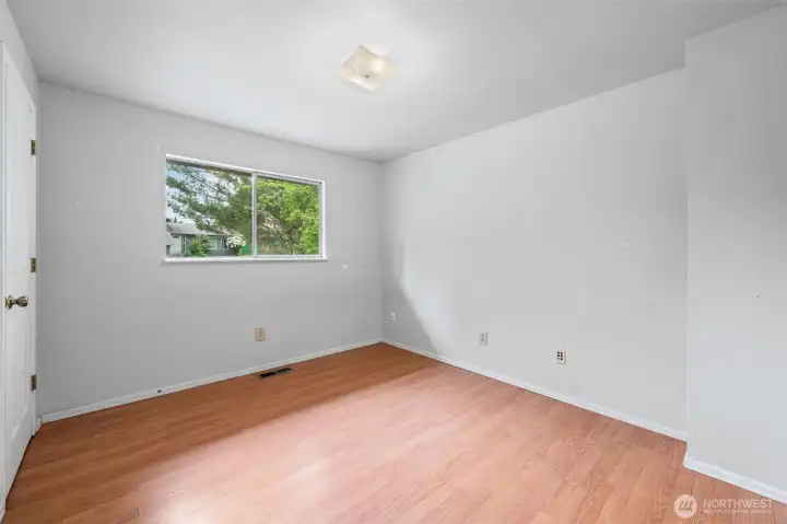 Bedroom Three features bright natural light, a view of blooming trees just outside the window, and laminate flooring. The kind of room that becomes whatever your needs are.