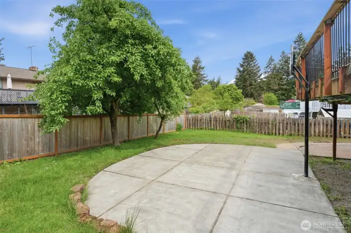 Fully fenced, concrete sport pad already poured, mature shade tree providing natural privacy — the outdoor bones are done.